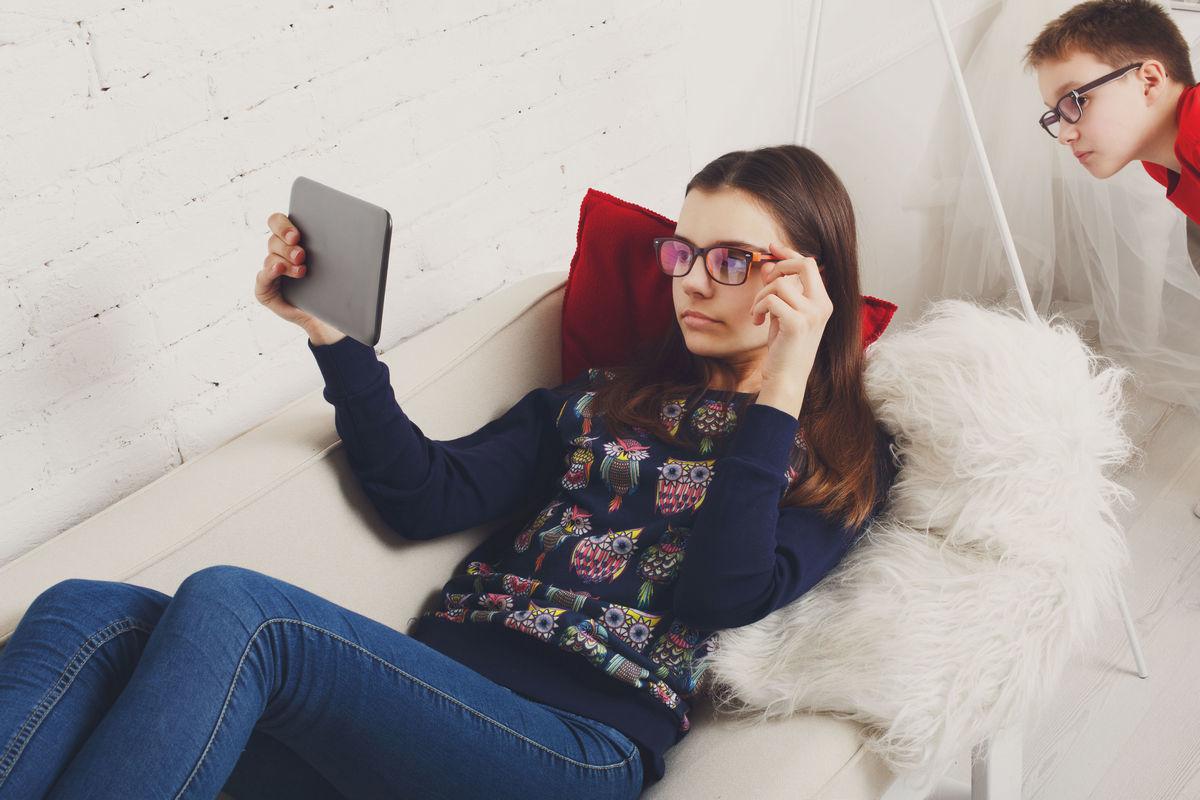 девушка лежит на диване в очках и читает 