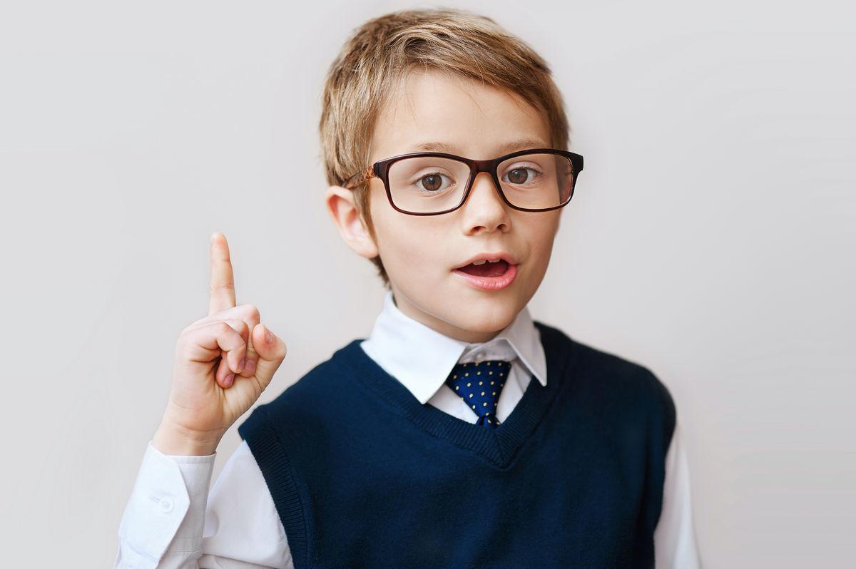 кареглазый мальчик в очках рубашке и галстуке поднимает указательный палец вверх